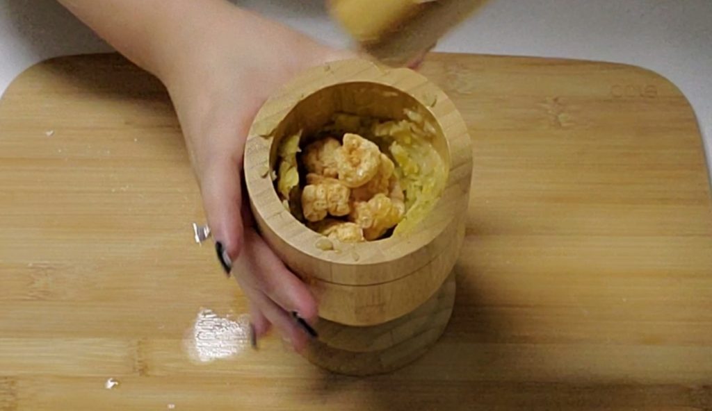 In a pilon or mortar, mash the fried green plantains to make puerto rican mofongo.