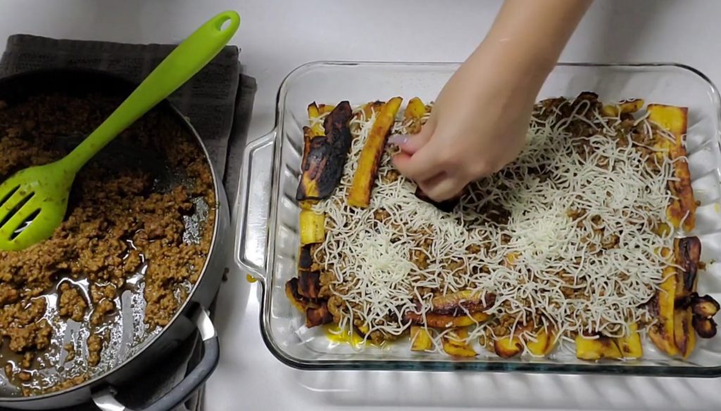Assemble Pastelon similar to any lasagna recipe. Start with strips of sweet plantains, followed by picadillo and cheese. 